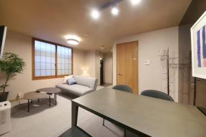 Una sala de estar con un sofá, una mesa y sillas. en ぷふか芝公園　(Pufuka Shibakoen), en Tokio