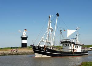 a black and white boat in the water with a lighthouse at LM7-9 - Ferienwohnung Typ B Komfort in Schottwarden
