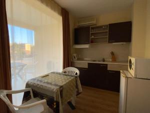 eine kleine Küche mit einem Tisch und einem Kühlschrank in der Unterkunft VECHNA R 18 Studio Sunny Beach in Sonnenstrand