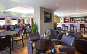 um restaurante com mesas e cadeiras e um bar em Holiday Inn Express Warwick - Stratford-upon-Avon, an IHG Hotel em Warwick