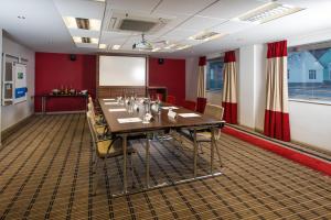 Holiday Inn Express Warwick - Stratford-upon-Avon, an IHG Hotel في وارويك: قاعة المؤتمرات مع طاولة وكراسي طويلة