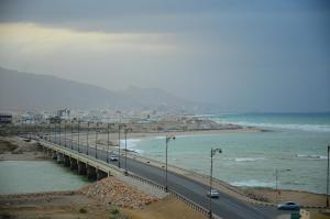 a bridge over a beach with cars on it at Al Faisal Hotel Suites in Sur