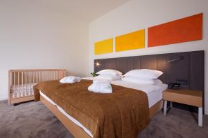 een slaapkamer met 2 bedden met kussens en een wieg bij Terme Tuhelj Hotel Well in Tuheljske Toplice +37 foto's