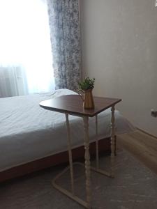 une table avec une plante à côté d'un lit dans l'établissement 1-ком.квартира от ИП Дома света, перекресток Кенесары-Кумисбекова, à Astana