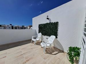 een balkon met 2 stoelen en een kat aan een muur bij Getaway To Cozy Home 4 Br, 35 B in Santo Domingo