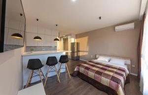 ein Schlafzimmer mit einem Bett und eine Küche mit Hockern in der Unterkunft Апартаменты метро Вырлица in Kiew