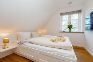 ein weißes Schlafzimmer mit einem großen weißen Bett und einem Fenster in der Unterkunft Ferienwohnung Käthe in Wenningstedt-Braderup