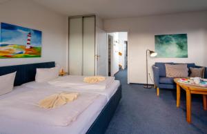 ヴェニングシュテットにあるHaus Düneneckのベッド2台とソファが備わるホテルルームです。