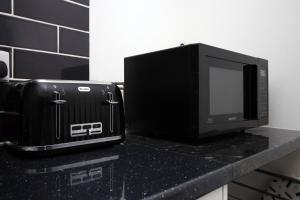 a microwave sitting on top of a counter next to a toaster at Executive Style 2 Bed Flat in Bridgend F2 in Bridgend +18 photos