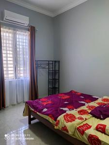 um quarto com uma cama com um cobertor roxo e amarelo em The Family Guesthouse em Kota Bharu