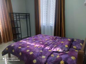 a bed with a purple comforter with yellow stars at The Family Guesthouse in Kota Bharu
