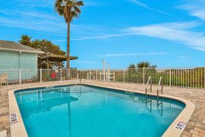 ein großer blauer Pool mit einem Zaun und einer Palme in der Unterkunft Indian Sunset Beach 7 in Clearwater Beach