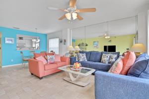 W salonie znajdują się niebieskie i różowe meble oraz wentylator sufitowy. w obiekcie Indian Sunset Beach 7 w mieście Clearwater Beach