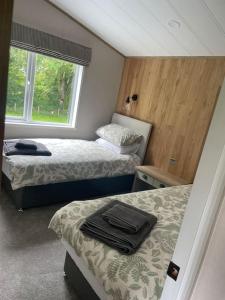 a bedroom with two beds and a window at Snittlegarth Farm Lodges in Wigton