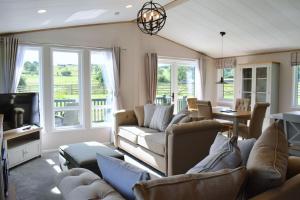 a living room with couches and a tv and windows at Snittlegarth Farm Lodges in Wigton