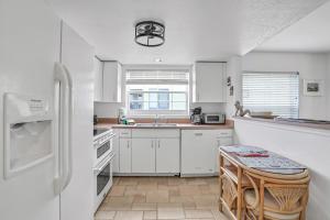 a kitchen with white cabinets and a white refrigerator at Indian Sunset Beach 7 in Clearwater Beach