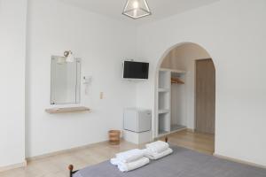 een kamer met witte muren, een tv en handdoeken bij Oscar Hotel in Kamari
