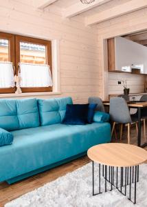 uma sala de estar com um sofá azul e uma mesa em Domki Gorczański Zakątek - Jacuzzi em Nowy Targ
