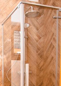 prysznic ze szklanymi drzwiami i drewnianą podłogą w obiekcie Domki Gorczański Zakątek - Jacuzzi w Nowym Targu