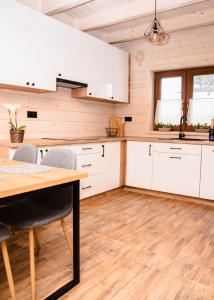 a kitchen with white cabinets and a wooden floor at Domki Gorczański Zakątek - Jacuzzi in Nowy Targ