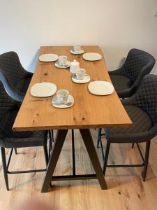 uma mesa de madeira com cadeiras, copos e pratos em Apartment Relax - Stubenbergsee em Stubenberg