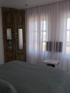 a bedroom with a bed and two windows with curtains at Portobello River and Sea View in Alvor