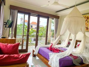 a bedroom with two beds with curtains and a balcony at Merthayasa Bungalow 2 in Ubud