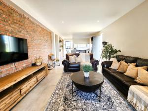 a living room with a couch and a brick wall at Kabeljauws Beach Apartments in Jeffreys Bay