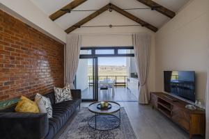 a living room with a couch and a brick wall at Kabeljauws Beach Apartments in Jeffreys Bay