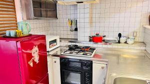 uma cozinha com um fogão e um frigorífico vermelho em 田町ハウス em Takamatsu