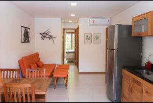 cocina y sala de estar con nevera y mesa en Flat Vila Taipu, en Maraú