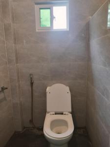 a bathroom with a white toilet with a window at Bais City Home Staycation in Bais