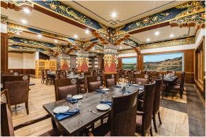 a restaurant with a long table and chairs andwindows at The Gawaling ladakh in Leh