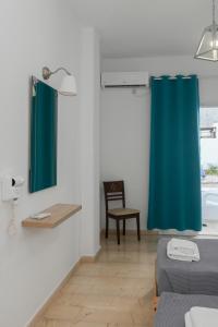 a room with a blue shower curtain and a chair at Oscar Hotel in Kamari