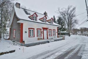 una casa roja y blanca en la nieve en Om chalet 1 avec spa face au fleuve, en Saint-Jean