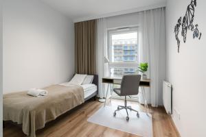 a bedroom with a bed and a desk and a chair at Lwowska Apartment by the Malta Lake Poznań by Renters in Poznań