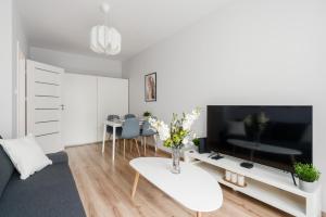 a living room with a large television and a table at Lwowska Apartment by the Malta Lake Poznań by Renters in Poznań