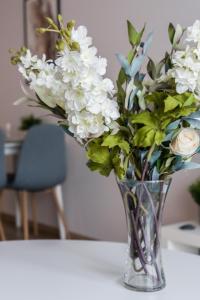 a vase filled with white flowers on a table at Lwowska Apartment by the Malta Lake Poznań by Renters in Poznań