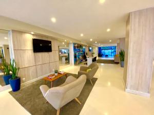 a living room with chairs and a tv on a wall at HANNA Arcos d'Atalaia Hotel - Aracaju in Aracaju