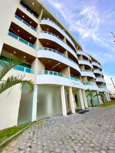 a large building with a palm tree in front of it at HANNA Arcos d'Atalaia Hotel - Aracaju in Aracaju
