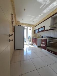 a kitchen with a refrigerator and a tile floor at 3-1квартира с бассейном в 2,5 км от моря in Altınkum