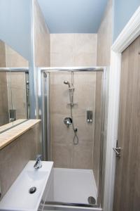 uma casa de banho com um chuveiro e um lavatório. em Westciti Caroco Aparthotel em Croydon