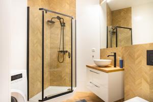 La salle de bains est pourvue d'une douche et d'un lavabo. dans l'établissement ApartamentySnu, Struga Tower Deep Purple, à Radom