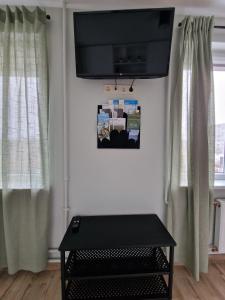 Apartamenti Jēkabpilī في جيكاببيلس: غرفة بها طاولة سوداء وتلفزيون على جدار