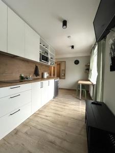 a kitchen with white cabinets and a wooden floor at Apartamenti Jēkabpilī in Jēkabpils