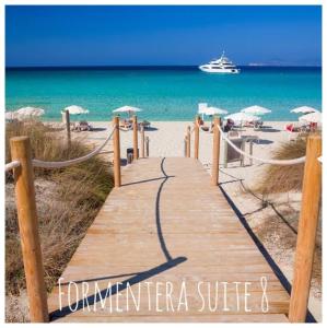 un camino de madera a la playa con un crucero en el fondo en Formentera Suite 8 en Es Pujols