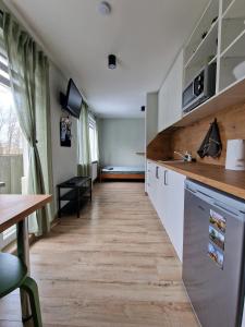 a kitchen with white cabinets and a wooden floor at Apartamenti Jēkabpilī in Jēkabpils