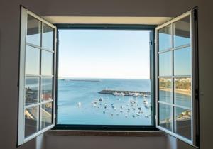 a window with a view of a beach and the ocean at Manas Coliving in Sines