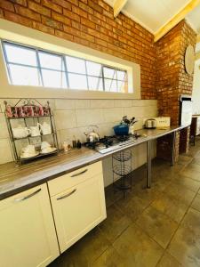 uma cozinha com um balcão e uma parede de tijolos em East of East Guest Cottage em Avondzon