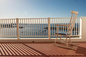 a rocking chair sitting on a balcony overlooking the ocean at Manas Coliving in Sines
